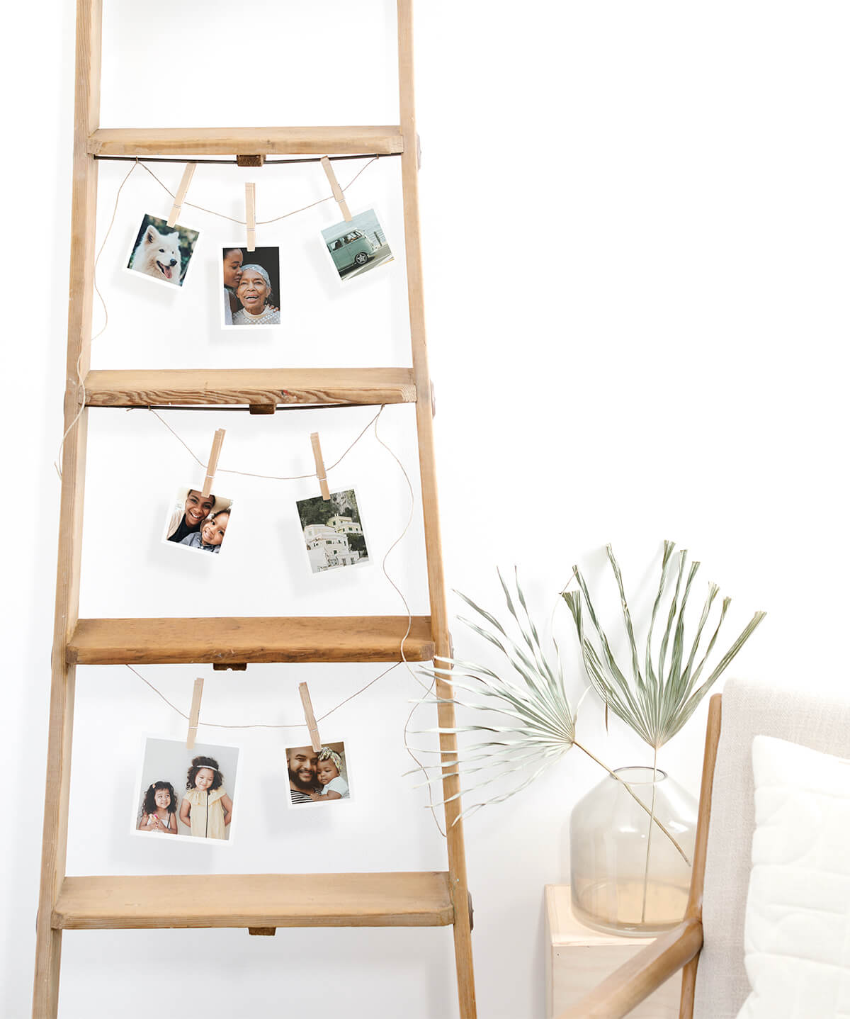 Photo prints hanging from rungs of wooden ladder
