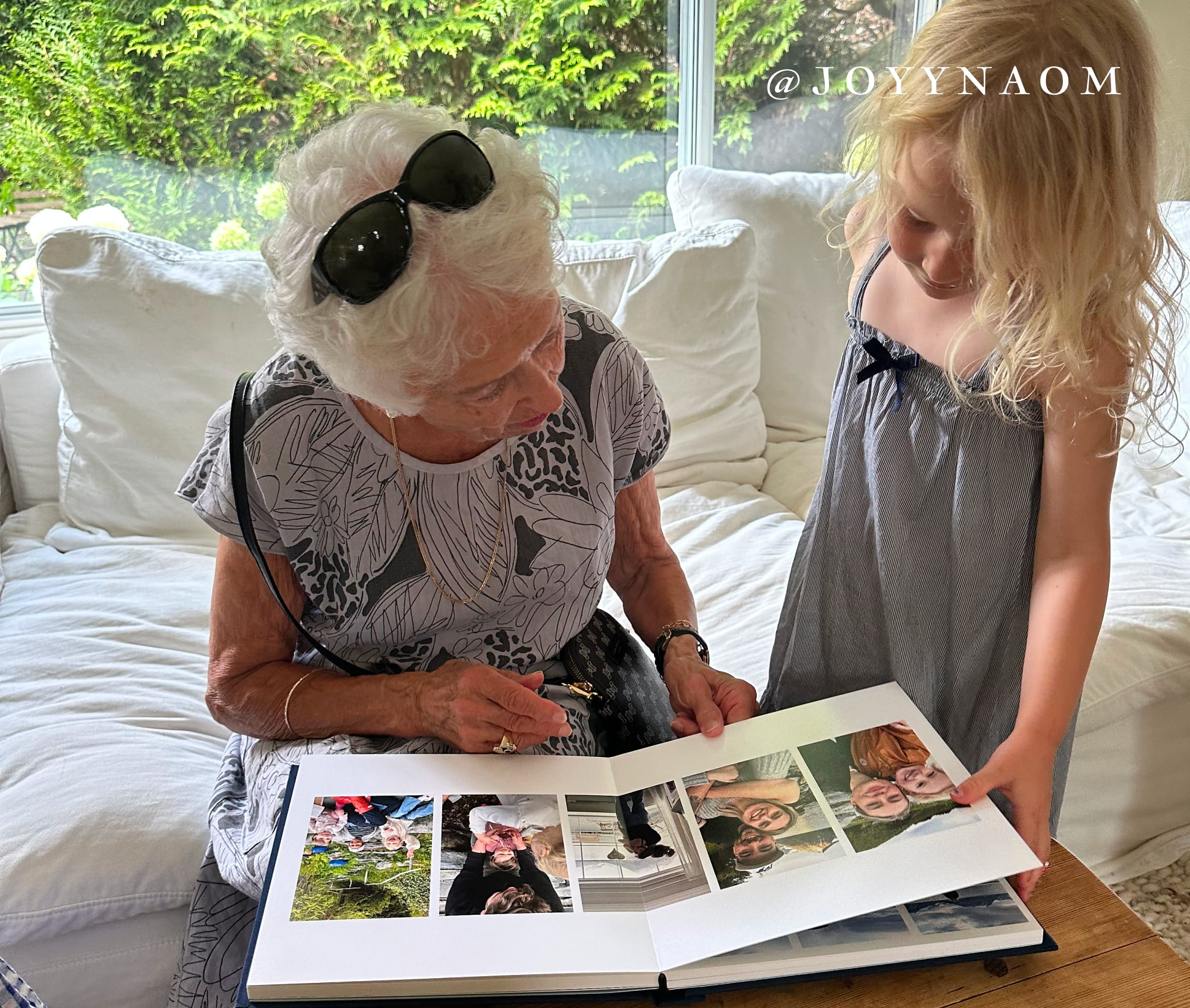 image of grandmother and granddaughter looking at their layflat photo album reminiscing on memories together